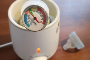 Babyflasche im Flaschenwärmer mit Thermometer zur Temperaturkontrolle