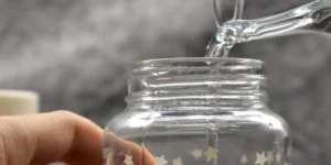 Wasser wird in eine Babyflasche aus Glas gegossen