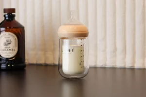 Babyflasche aus Doppelglas mit Milch auf einem Tisch